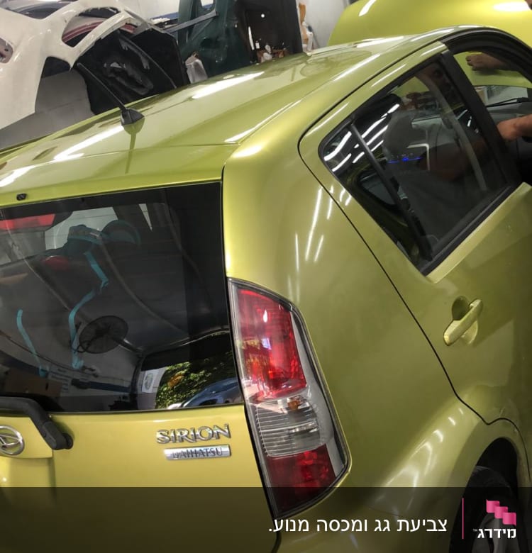 מכונית ירוקה במוסך עם חלקי רכב נוספים